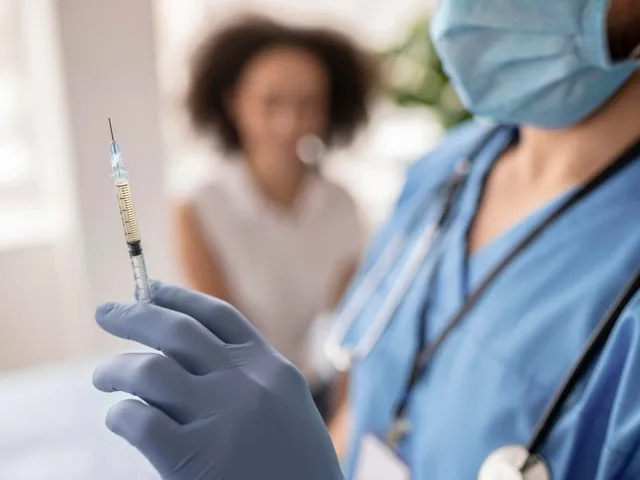 Врач-гинеколог беседует с пациенткой, держа в руках символическую ленту поддержки